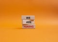 We are Hiring symbol. Concept words We are Hiring on wooden blocks. Beautiful orange background. Business and We are Hiring