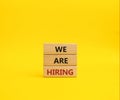 We are Hiring symbol. Concept words We are Hiring on wooden blocks. Beautiful yellow background. Business and We are Hiring