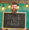 Hiring teachers concept. Man with beard and mustache on happy face welcomes colleagues, chalkboard on background