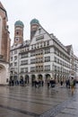 Feb 2, 2020 - Munich, Germany: HIRMER House on street of Munchen with domed towers of Gotchic church Frauenkirche