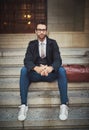 His brand of style is urban. Portrait of a stylish young man sitting on steps in the city. Royalty Free Stock Photo