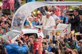 His Holiness Pope Francis sitting at Pope Mobile and waving to crowd with Latvian and Vatican flags.