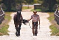 His horse is his best friend. Rearview shot of a cowboy leading his horse by the reins. Royalty Free Stock Photo