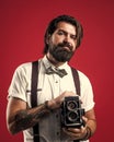 his new style. mature journalist use old technology. bearded camera man in suspenders. brutal guy photographer wear bow