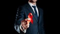 His support. Red ribbon in hiv world day in man hand. Awareness aids and cancer symbol isolated on black background Royalty Free Stock Photo