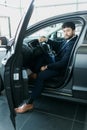 Portrait of a mature man smiling happily sitting in a brand new car touching the dashboard Royalty Free Stock Photo