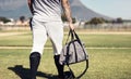 His whole life is in that bag. a man walking onto a baseball field.