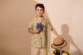 Hispanic adorable smiling teen boy traveler tourist holds passport document, standing near a suitcase, studio background Royalty Free Stock Photo