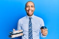 Hispanic adult business man holding take away coffee and sweets sticking tongue out happy with funny expression Royalty Free Stock Photo