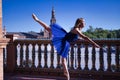 Hispanic adult female classical ballet dancer in blue tutu doing figures on the terrace of a plaza next to a beautiful tiled