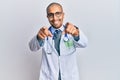 Hispanic adult man wearing doctor uniform and stethoscope pointing to you and the camera with fingers, smiling positive and Royalty Free Stock Photo