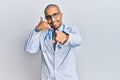 Hispanic adult man wearing doctor uniform and stethoscope smiling doing talking on the telephone gesture and pointing to you Royalty Free Stock Photo
