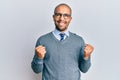 Hispanic adult man wearing glasses and business style excited for success with arms raised and eyes closed celebrating victory Royalty Free Stock Photo