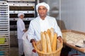 Hispanic baker showing fresh baked baguettes in bakery Royalty Free Stock Photo