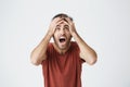 Hispanic beardy man in red shirt expressive react on bad news from work getting about his boss. Unhappy guy