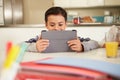 Hispanic Boy Doing Homework At Table Using Digital Tablet Royalty Free Stock Photo