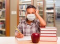 Hispanic Boy Wearing Face mask with Books, Apple, Pencil and Paper at Library Royalty Free Stock Photo