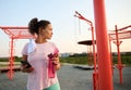 Athletic woman on a sports field with smartphone and bottle with water