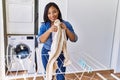 Hispanic brunette woman hanging clean laundry on rack at laundry room Royalty Free Stock Photo