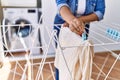 Hispanic brunette woman hanging clean laundry on rack at laundry room Royalty Free Stock Photo