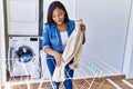 Hispanic brunette woman hanging clean laundry on rack at laundry room Royalty Free Stock Photo