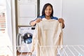 Hispanic brunette woman hanging clean laundry on rack at laundry room Royalty Free Stock Photo