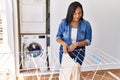 Hispanic brunette woman hanging clean laundry on rack at laundry room Royalty Free Stock Photo