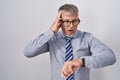 Hispanic business man with grey hair wearing glasses looking at the watch time worried, afraid of getting late Royalty Free Stock Photo