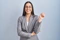 Hispanic business woman wearing glasses with a big smile on face, pointing with hand and finger to the side looking at the camera Royalty Free Stock Photo