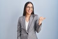 Hispanic business woman wearing glasses smiling with happy face looking and pointing to the side with thumb up Royalty Free Stock Photo