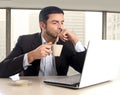 Hispanic businessman holding cup of coffee sitting at business district office desk working Royalty Free Stock Photo