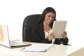 Hispanic businesswoman sitting at office computer desk smiling happy using digital tablet Royalty Free Stock Photo