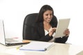 Hispanic businesswoman sitting at office computer desk smiling happy using digital tablet Royalty Free Stock Photo