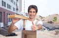 Hispanic carpenter on construction site showing thumb