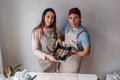 Hispanic couple preparing cinnamon rolls from home with white wall background