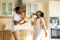 hispanic couple singing together holding a ladle like a microphone in the kitchen Royalty Free Stock Photo