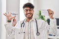 Hispanic doctor man with beard holding covid record card celebrating victory with happy smile and winner expression with raised