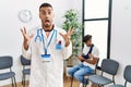 Hispanic doctor man at waiting room with pacient with arm injury celebrating victory with happy smile and winner expression with