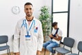 Hispanic doctor man at waiting room with pacient with arm injury looking positive and happy standing and smiling with a confident