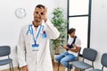 Hispanic doctor man at waiting room with pacient with arm injury smiling happy doing ok sign with hand on eye looking through