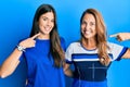 Hispanic family of mother and daughter wearing casual clothes over blue background smiling cheerful showing and pointing with