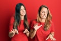 Hispanic family of mother and daughter wearing casual clothes over red background disgusted expression, displeased and fearful Royalty Free Stock Photo