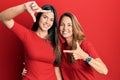 Hispanic family of mother and daughter wearing casual clothes over red background smiling making frame with hands and fingers with Royalty Free Stock Photo