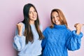 Hispanic family of mother and daughter wearing wool winter sweater pointing to the back behind with hand and thumbs up, smiling Royalty Free Stock Photo