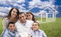 Hispanic Family Sitting in Grass Field with Ghosted House Behind Royalty Free Stock Photo