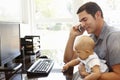 Hispanic father with baby working in home office Royalty Free Stock Photo