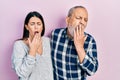 Hispanic father and daughter wearing casual clothes bored yawning tired covering mouth with hand