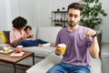 Hispanic father of interracial family drinking a cup coffee pointing down looking sad and upset, indicating direction with Royalty Free Stock Photo