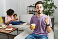 Hispanic father of interracial family drinking a cup coffee pointing up looking sad and upset, indicating direction with fingers, Royalty Free Stock Photo