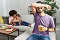 Hispanic father of interracial family drinking a cup coffee smiling cheerful playing peek a boo with hands showing face Royalty Free Stock Photo